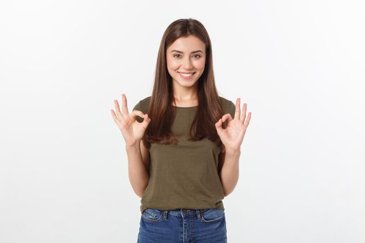 Happy young woman showing ok sign with fingers an winking isolated on a gray background
