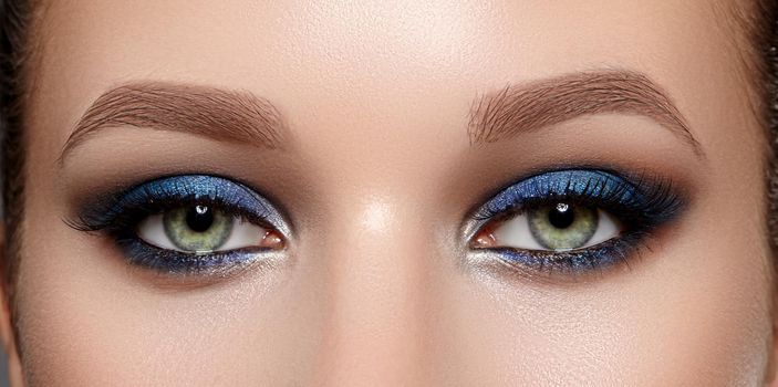 Closeup Macro of Woman Face with Green Eyes Make-up. Fashion Indigo Celebrate Makeup, Glowy Clean Skin, perfect Shapes of Brows. Shiny Shimmer