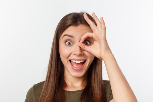 Close up portrait of cheerful, cute, stylish,attractive, trendy girl making binoculars with fingers, isolated on grey background, having good mood.