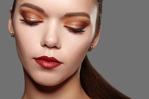 Beautiful Woman with Professional Makeup. Party Gold Eye Make-up, Perfect Eyebrows, Shine Skin. Bright Fashion Look with Red Lips