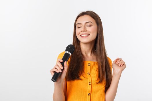 Young pretty woman happy and motivated, singing a song with a microphone, presenting an event or having a party, enjoy the moment.