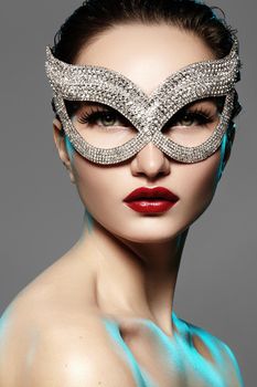 Beautiful Model with Fashion luxe Lips Make-up wearing bright brilliant mask. Masquerade style woman. Holiday celebration look