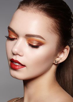 Closeup portrait of Woman Face with Gold glitter Make-up, bright red liner on Eyes. Fashion Celebrate Makeup, Glowy Skin. Shiny Simmer and metalic eye shadows