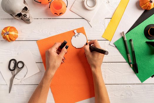 Happy Halloween concept. Step by step instruction of making halloween bookmark DIY pumpkin craft. Step 3 - draw out a pumpkin shape on a piece of paper or felt. Top view flat lay