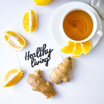 HEALTHY LIVING - written on piece of paper among the products for the treatment of common cold - lemon, ginger, chamomile tea. Vitamin natural drink. Cinnamon anise star.