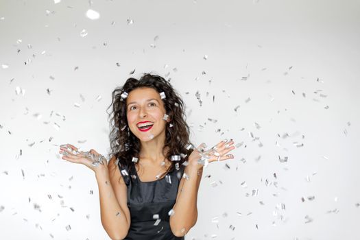 The emotion of success. Happy sexy brunette girl is enjoying celebrating with confetti on a white background.