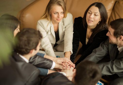 Close-up of business partners making pile of hands at meeting