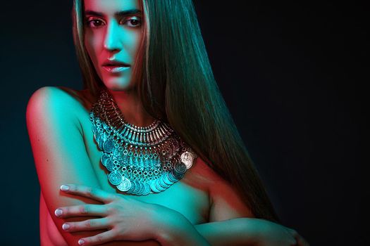 Beautiful woman in a necklace. Model in jewelry from silver. Beautiful indian jewellery. Bright lights photo effect