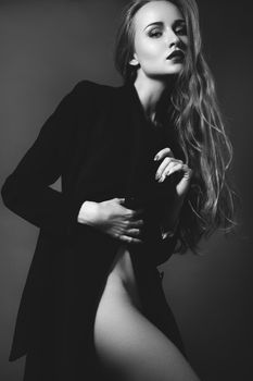 Sexy lady in Elegant Coat. Beautiful model in Fashion Jacket with Long Curly Hair. Erotic style. Black and White shot on grey background