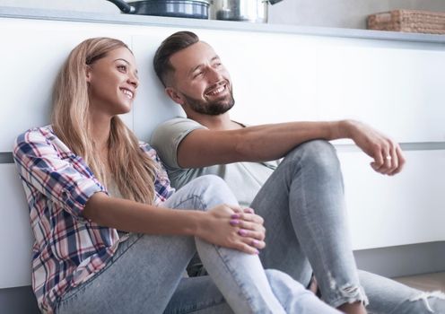 close up. the happy couple discussing something sitting on the kitchen floor