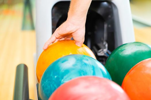 Young man playing bowling at the sport club.