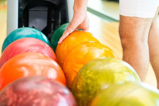 Young man playing bowling at the sport club.