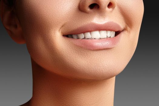Wide smile of young beautiful woman with perfect healthy white teeth on grey background. Dental whitening, ortodont, care tooth and wellness. Natural makeup on perfect face.