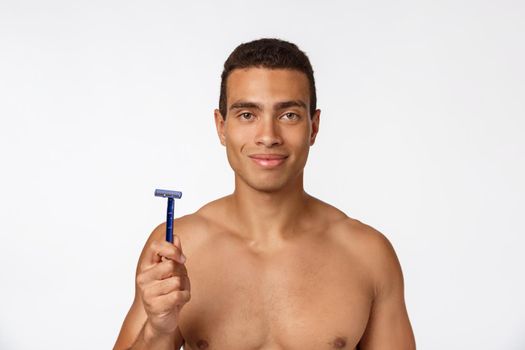 Close up of a happy naked african man holding razor isolated over gray background