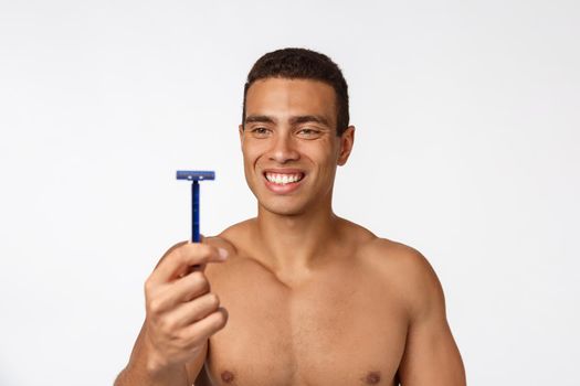 Close up of a happy naked african man holding razor isolated over gray background