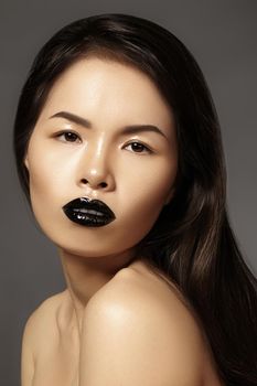 High Fashion Beauty Asian Model with bright Lip Gloss Make-up. Black Lips with gloss lipstick makeup. Long dark hair. Vertical photo