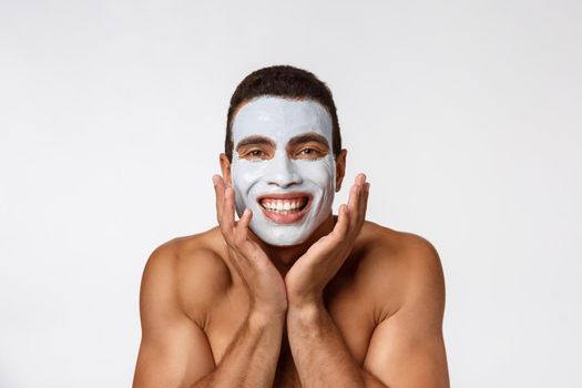 Picture of cheerful nice young african guy smiling on camera. Portrait of man with cream mask on cheeks. Beauty routine.