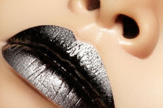 Macro close-up of female mouth. Sexy black Gloss Lips with silver glitter Makeup. Halloween Style Make-up with dark lipstick. Shiny celebrate visage