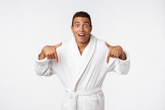 African american guy wearing a bathrobe pointing finger with surprise and happy emotion. Isolated over whtie background