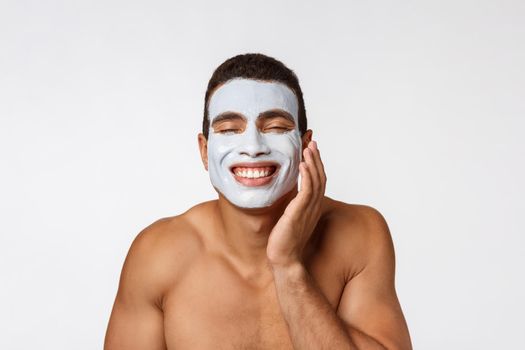 Picture of cheerful nice young african guy smiling on camera. Portrait of man with cream mask on cheeks. Beauty routine.