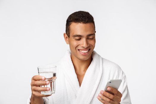 An attractive man drinking a glass of water against white background.