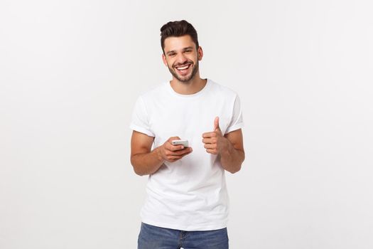 Happy casual man with smartphone and thumb up over gray background.