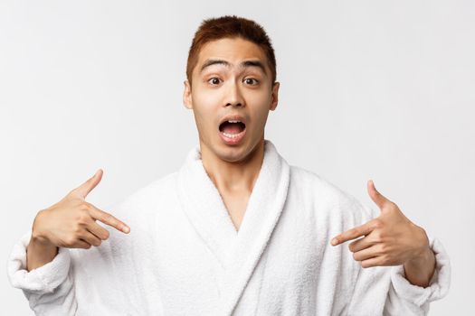 Beauty, spa and leisure concept. Portrait of surpirsed and amazed young asian man heard great news and pointing fingers himself, look camera disbelief react to unexpected win, white background.