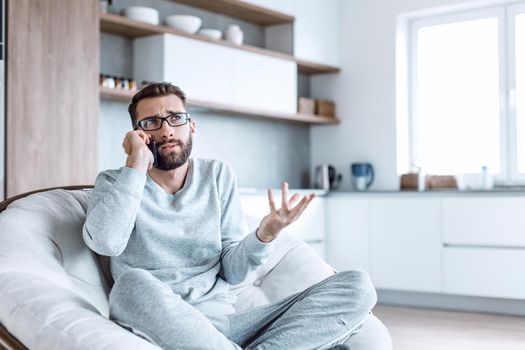 cheerful man talking on a mobile phone sitting in a comfortable chair. photo with copy space