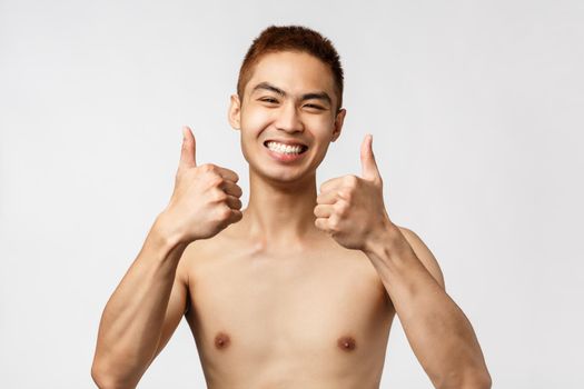 Beauty, people and home concept. Close-up portrait of satisfied, excited asian man standing naked, smiling upbeat, feel enthusiastic and rejoicing, standing white background, give approval.