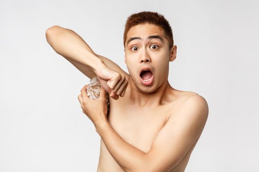 Beauty, people and hygiene concept. Portrait of startled and scared naked handsome asian guy open mouth, gasping alarmed as someone enter bathroom while he washing nude white background.