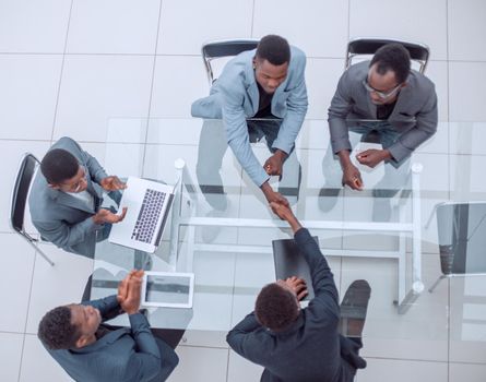 top view. business partners shaking hands during negotiations in the office