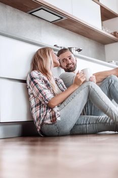 close up. young couple drinking coffee sitting on the kitchen floor