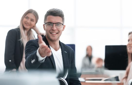 close up. smiling business man sitting at an office Desk and pointing at you.