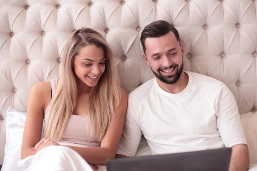 young couple browsing their favorite vidio on their laptop in the bedroom.