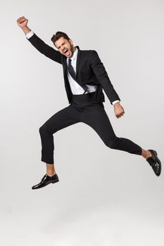 Portrait of a happy businessman jumping in air against isolated white background