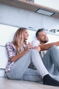 close up. young couple drinking coffee sitting on the kitchen floor