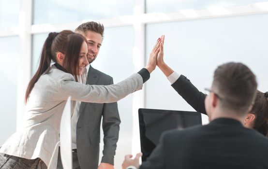 young employees giving each other a high five in the workplace. the concept of success