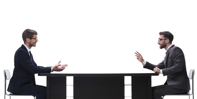 side view. two business people discussing something sitting at the table . isolated on white background