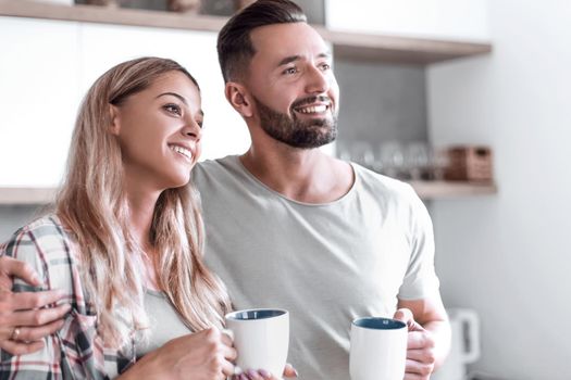 close up.young couple drinking coffee standing in the kitchen