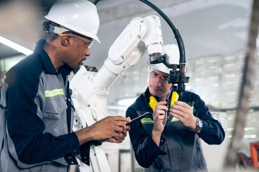 Factory workers working with adept robotic arm in a workshop . Industry robot programming software for automated manufacturing technology .