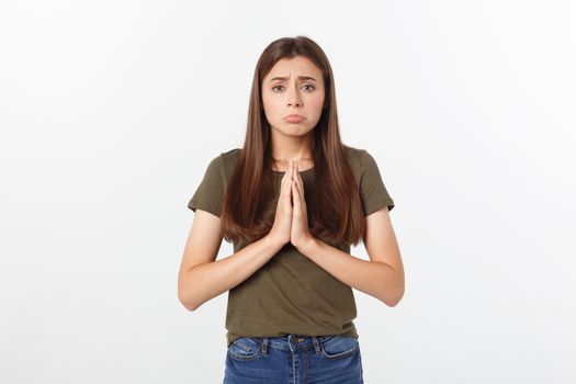 Beautiful young woman in casual clothes holding hands together and praying, isolated on white