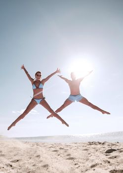 Happy couple jumping on the beach at sunset