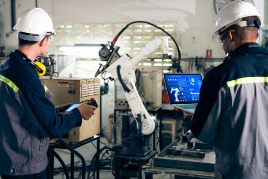 Factory workers working with adept robotic arm in a workshop . Industry robot programming software for automated manufacturing technology .