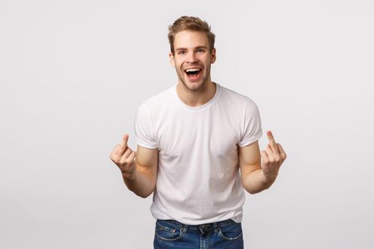 Rude and expressive, intollerant blond happy careless guy, dont care people opinion, fuck-off, showing middle fingers and cursing with smile on face, feeling daring and sassy, white background.