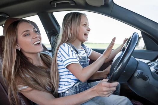 mom teaches her little daughter to drive.the concept of parenting