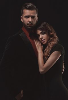 Portrait of young couple in love posing at studio dressed in classic clothes