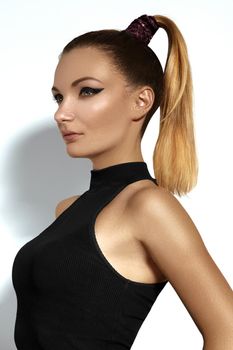 Fashion portrait of beautiful young woman with ponytail hairstyle. Beauty shot of sexy girl on white background. Pony tail straight hair, catwalk black eyeliner makeup on model face