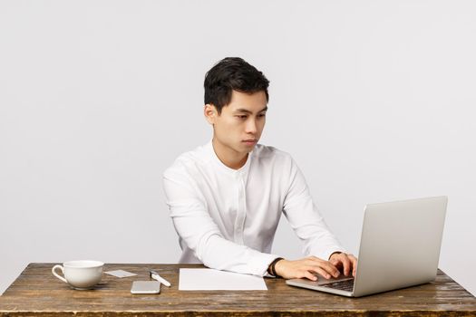 Working process, business and corporate concept. Handsome asian businessman in collar shirt, sitting office desk prepare report, working with laptop, contacting clients via mail, white background.