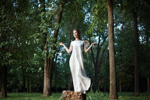 Beautiful Woman Posing like Goddess in White Long Dress at Nature. Boho Style, Spirit Calm, Wellness and Self-making. Freedom and Relaxing. Soul Health
