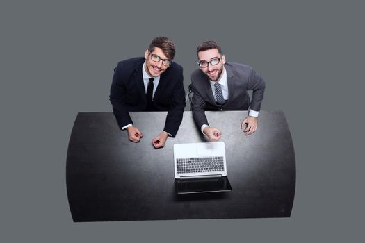 from the top view. smiling business colleagues sitting in front of an open laptop . isolated on white background